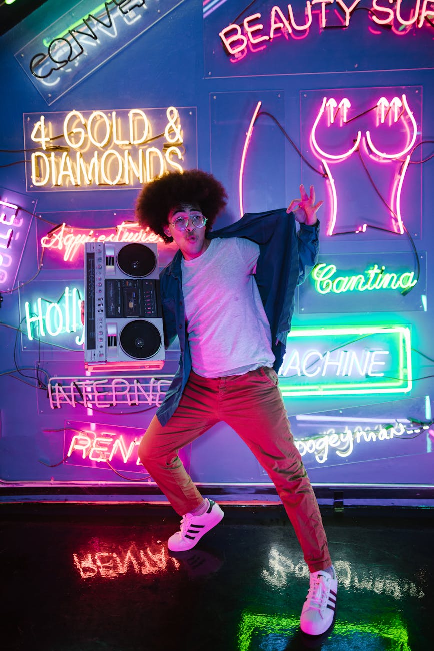 young man holding a cassette player near wall with neon lights